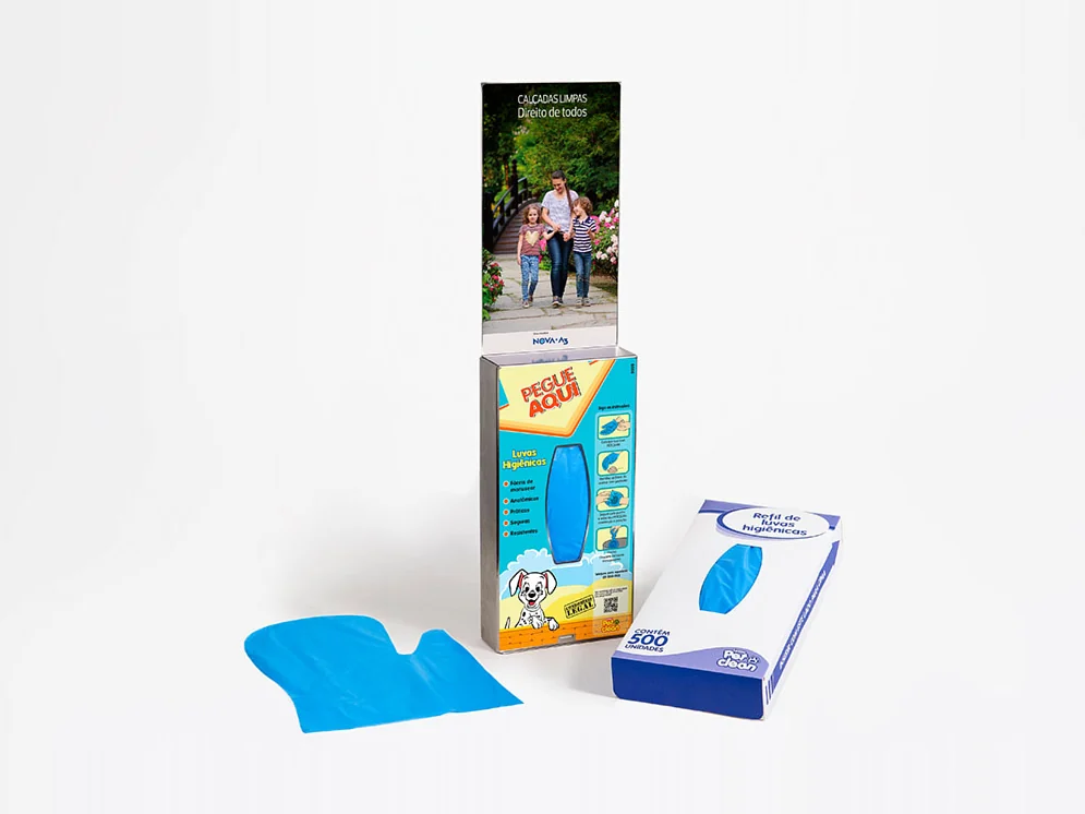 Dispenser Pet Clean em aço inox ao lado da caixa do Refil com 500 luvas higiênicas e de uma luva azul estendida, fotografados em fundo cinza de estúdio